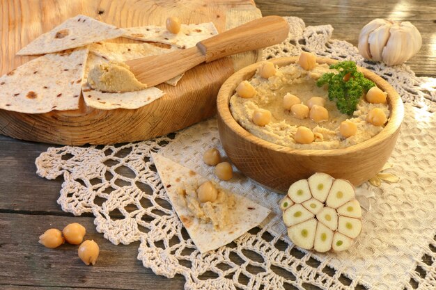 Hummus con pane pita e aglio su un tavolo di legno