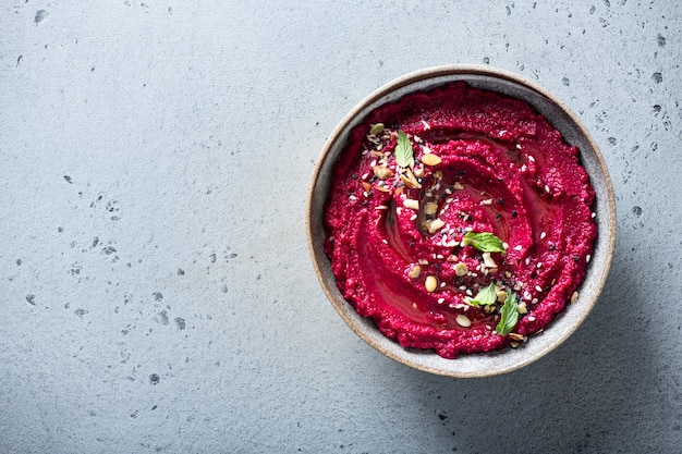 Hummus di barbabietola in una ciotola di ceramica su uno sfondo luminoso, vista dall'alto,