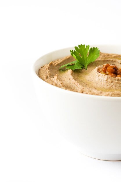 Hummus di lenticchia in ciotola isolata su bianco