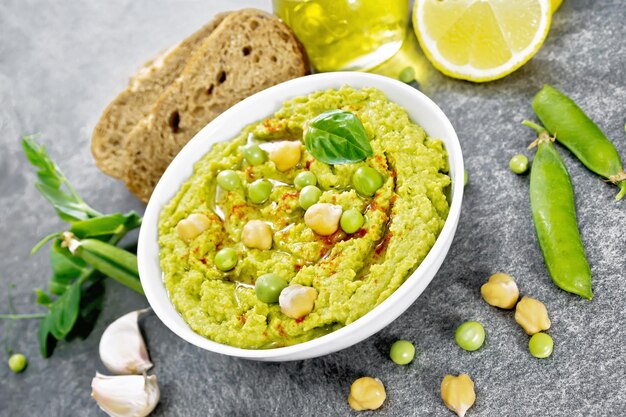 Hummus di piselli verdi in ciotola sul tavolo di granito