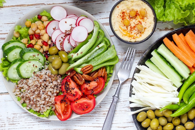 Hummus in ciotola, bastoncini di verdure, ceci, olive.