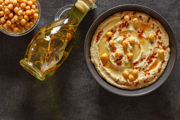 Hummus in una ciotola con spezie di olio d'oliva e ceci su sfondo scuro vista dall'alto spazio per copiare il testo