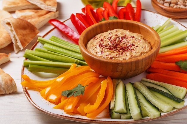 Hummus sano fatto in casa con verdure fresche assortite e pane pita.