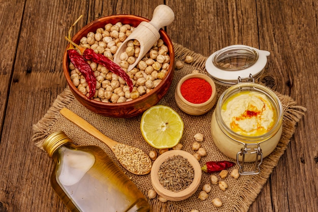 Hummus sulla vecchia tavola di legno. Ceci secchi, olio d'oliva, limone, cumino e peperoncino