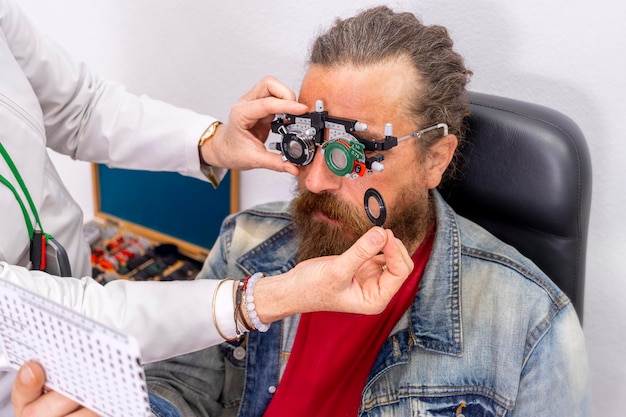 Hypster uomo che si laurea alla vista Medico ottico che mette le diottrie sugli occhiali