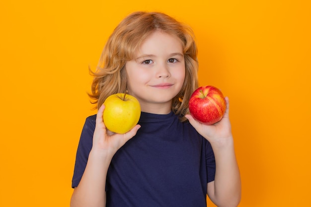 I bambini affrontano con la frutta Capretto con la mela in studio Studio ritratto di bambino carino tenere mela isolato su sfondo giallo