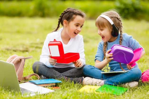 i bambini al picnic nel cortile della scuola stanno venendo a mangiare il pranzo nella scatola. genitore si occupa della custodia dei figli.