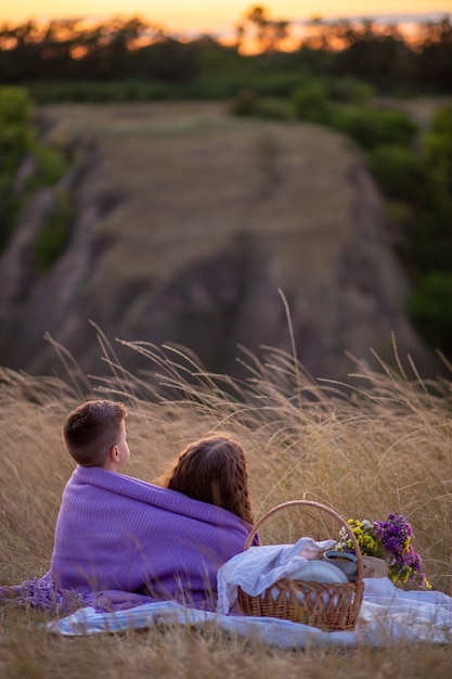 I bambini al tramonto si siedono a fare un picnic.