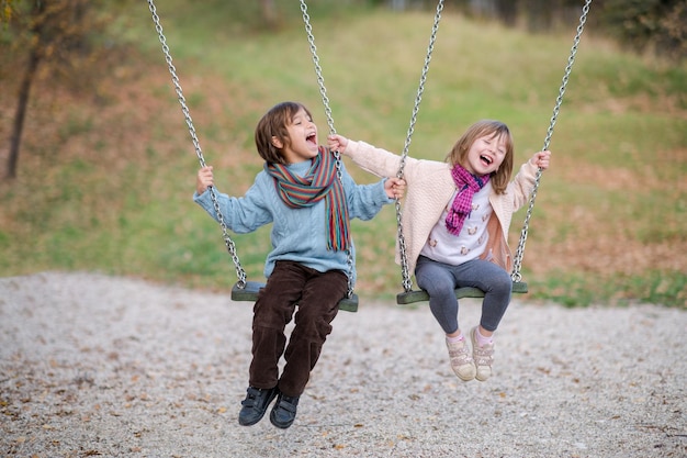 i bambini allegri si divertono su un'altalena fratellino e sorella che giocano fuori