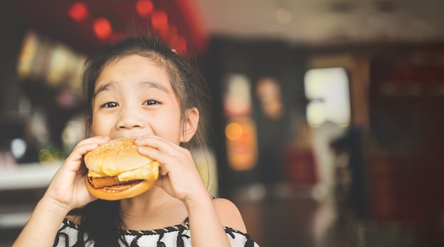 I bambini asiatici mangiano il pollo al formaggio Hamburger Food Court