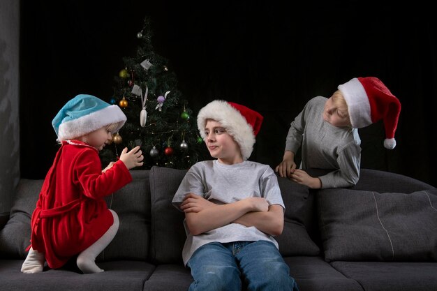 I bambini aspettano i regali di Natale. Tre bambini in cappelli di Babbo Natale.