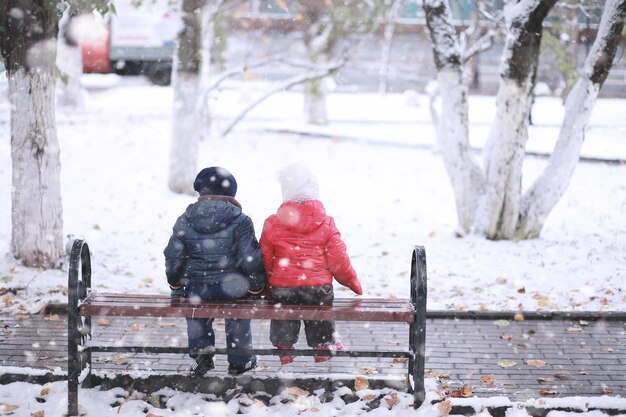 I bambini camminano nel parco con la prima neve