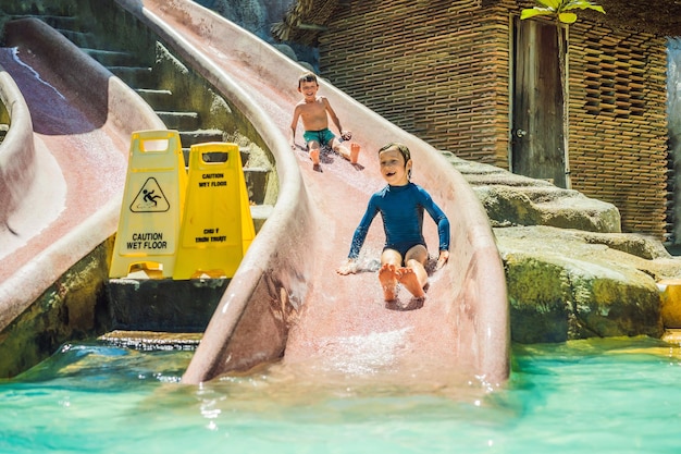 I bambini cavalcano uno scivolo d'acqua in un parco acquatico Infanzia felice