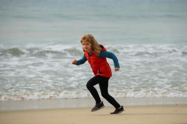 I bambini che corrono all'aperto corrono e fanno sport sano per i bambini bambino che corre vicino al mare fitness per bambini poco