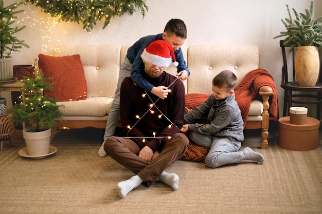 I bambini che legano il padre a immagine di Babbo Natale con la ghirlanda