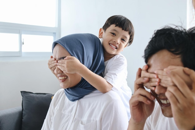 I bambini chiudono gli occhi dei genitori usando le mani dando una sorpresa il legame familiare a casa