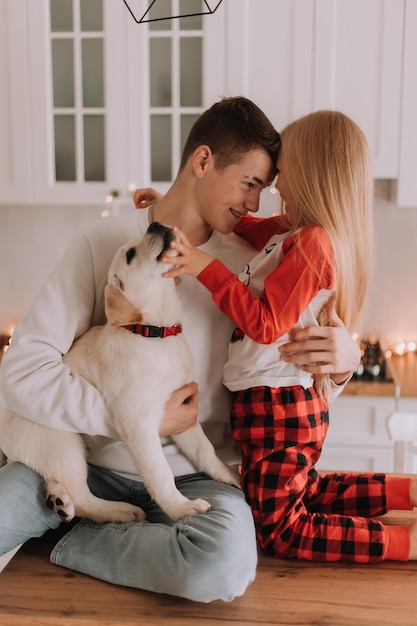 I bambini con il loro amato cane sono seduti nella cucina di Natale. passatempo familiare. stile di vita. fratello e sorella, ragazzo e ragazza giocano e scherzano con un animale domestico. spazio per il testo. Foto di alta qualità