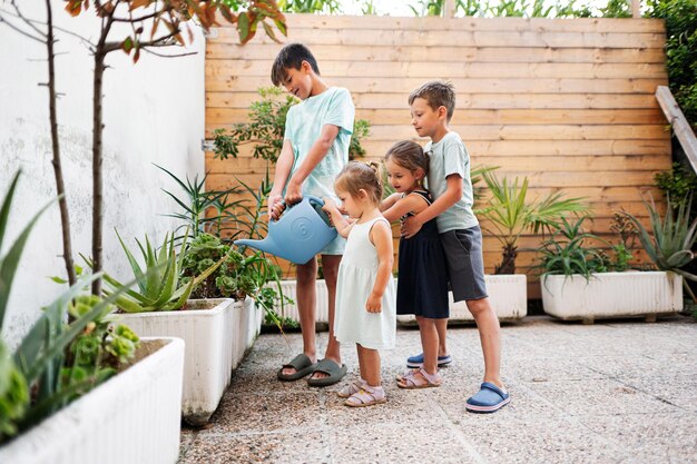 I bambini con latta innaffiano i fiori sulla terrazza della casa