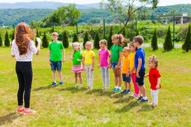 I bambini con tutor giocano all'aperto sul prato verde. Club estivo di recitazione e improvvisazione