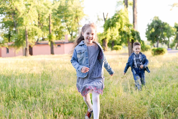 I bambini correnti emozionanti nel campo verde giocano insieme