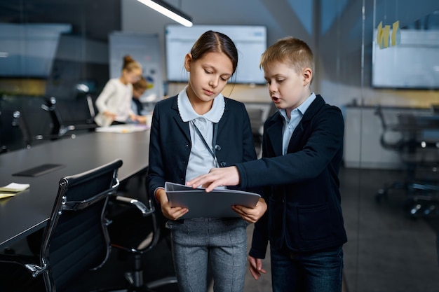 I bambini dei colleghi dipendenti che preparano i documenti per la riunione parlando insieme alla sala del consiglio