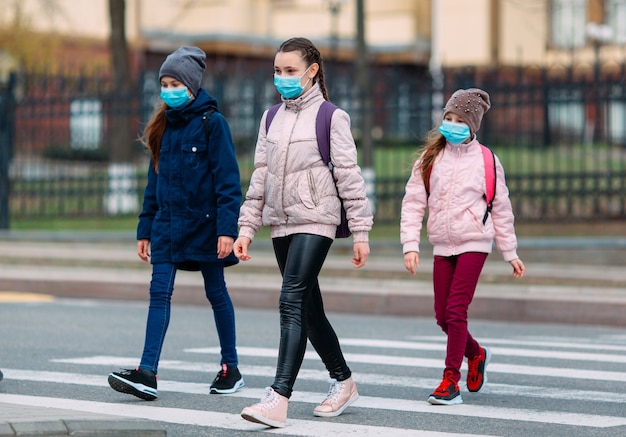 I bambini delle scuole attraversano la strada con maschere mediche