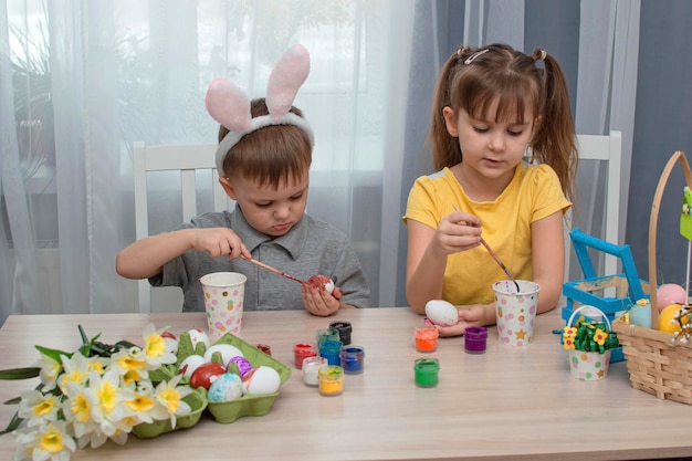 I bambini di buona Pasqua dipingono e disegnano le uova di Pasqua Bambini affascinanti che si preparano per le vacanze Ragazza e ragazzo carini decorano le uova di Pasqua