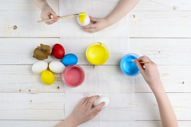 I bambini dipingono le uova per Pasqua sul tavolo di legno