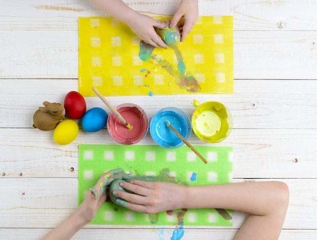 I bambini dipingono le uova per Pasqua sul tavolo di legno