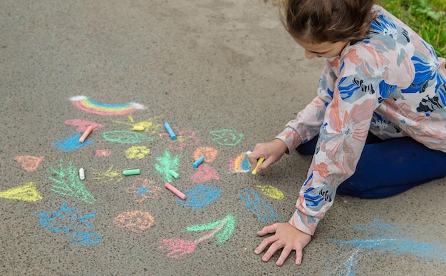 I bambini disegnano con il gesso sul marciapiede Fuoco selettivo