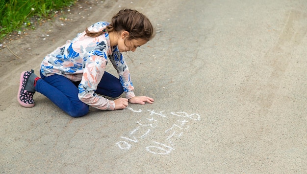 I bambini disegnano equazioni sul marciapiede con gesso Fuoco selettivo