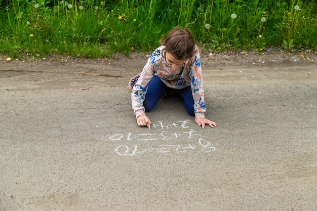 I bambini disegnano equazioni sul marciapiede con gesso Fuoco selettivo