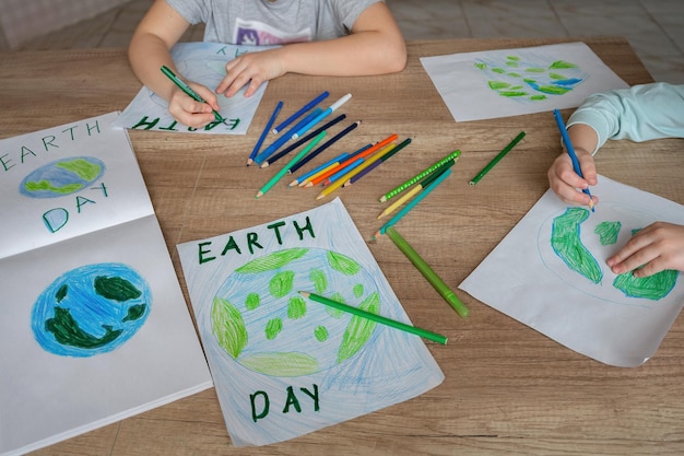 I bambini disegnano il pianeta Terra con matite e pennarelli su fogli di album per la Giornata della Terra