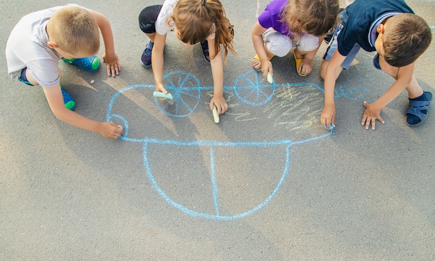 I bambini disegnano un&#39;auto con il gesso sul marciapiede