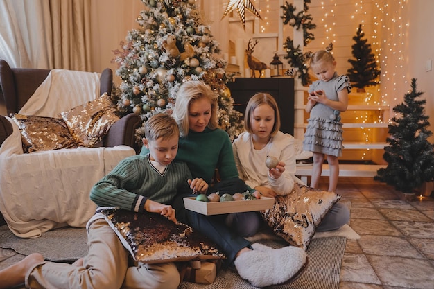 I bambini e la madre stanno decorando l'albero di Natale, Buon Natale e le vacanze di Capodanno. Famiglia, vacanze invernali e concetto di persone, famiglia amante del ritratto da vicino.