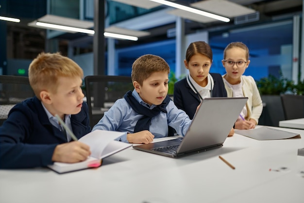 I bambini fanno brainstorming guardando lo schermo del laptop per discutere di qualcosa. Gruppo IT aziendale di Schoolkids