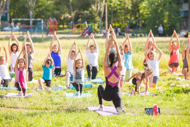 I bambini fanno yoga con un allenatore all&#39;aperto.