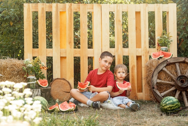I bambini felici mangiano l'anguria durante il picnic estivo all'aperto