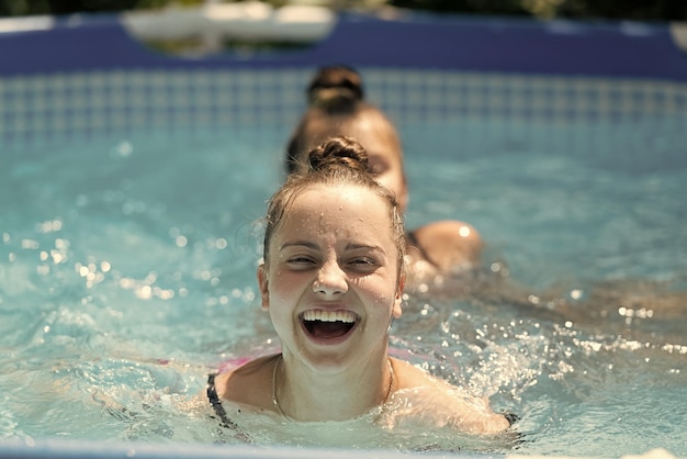 I bambini felici nuotano in piscina nelle soleggiate giornate estive estive