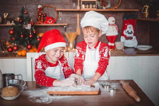 I bambini felici preparano i biscotti di Natale festosi nella cucina della casa la vigilia di Natale buon Natale e buone feste di Capodanno in famiglia