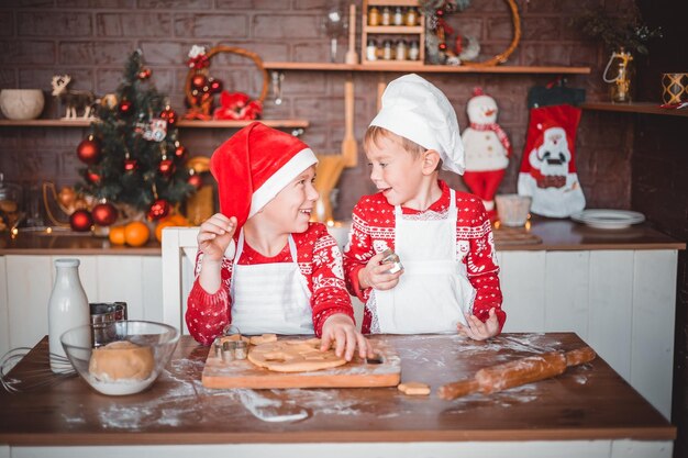 I bambini felici preparano i biscotti di Natale festosi nella cucina della casa la vigilia di Natale buon Natale e buone feste di Capodanno in famiglia