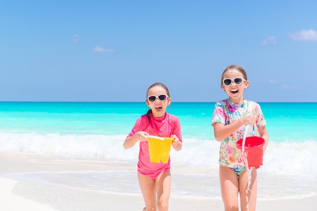 I bambini felici si divertono molto in spiaggia tropicale giocando insieme