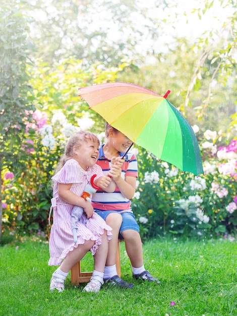 i bambini fratello e sorella sono in piedi con un ombrello sotto la pioggia