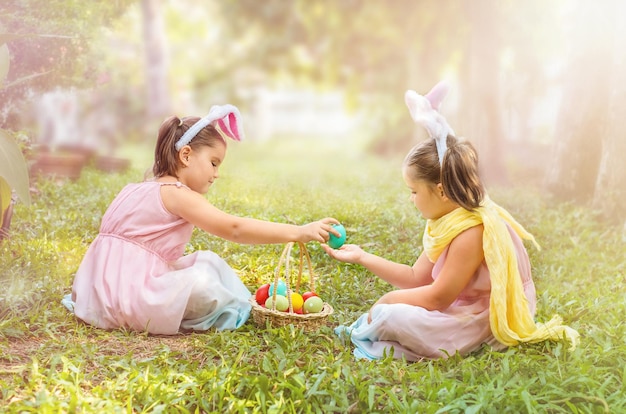 I bambini gemelli passano l'uovo di Pasqua nel cortile all'aperto