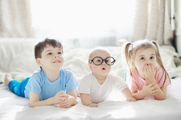 I bambini giacciono sul letto accanto al neonato, sorellina. Le emozioni dei bambini.