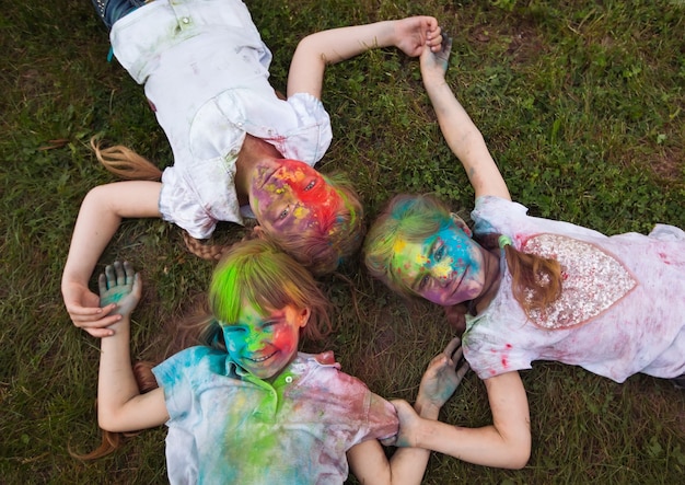 I bambini giacciono sull'erba. I bambini dipinti con i colori della festa di Holi giacciono sull'erba.