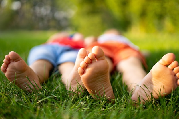 I bambini giacciono sull'erba nel parco in estate, le gambe dei bambini ravvicinate