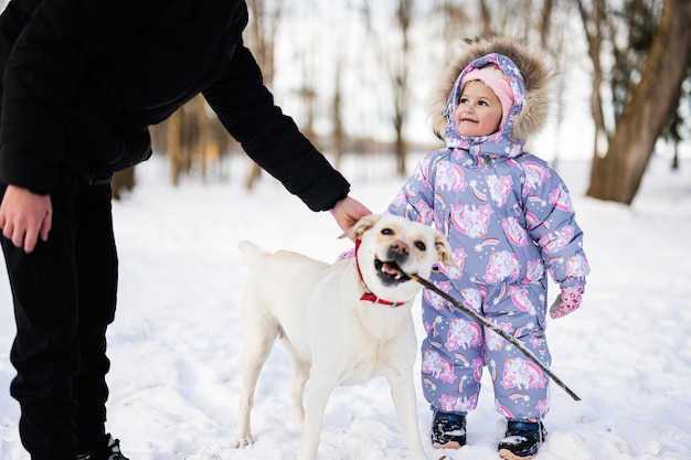 I bambini giocano con il cane labrador in una giornata invernale gelida e soleggiata nel parco