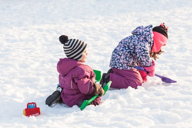 I bambini giocano con macchine e pale. Concetto di pulizia della neve in città