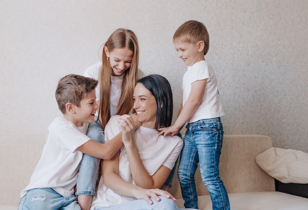 I bambini giocano e giocano con la madre seduta a casa sul divano.